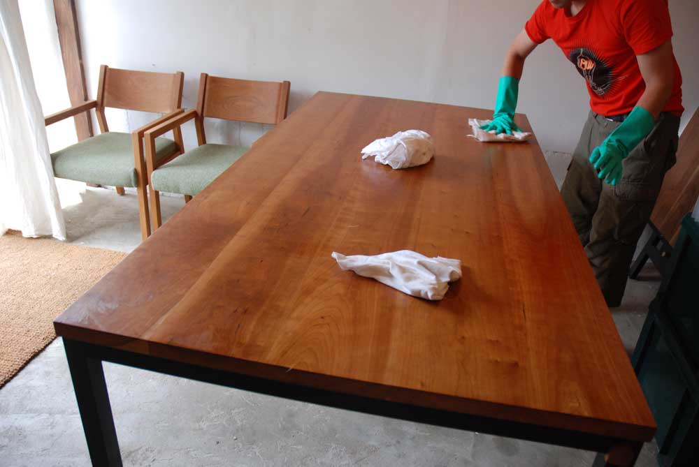 フィーデンワックスをブラックチェリー無垢材テーブルに塗りメンテナンス中の製作者の鳥部